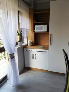 cocina con armarios blancos, microondas y ventana en Willa u Samków, en Zakopane