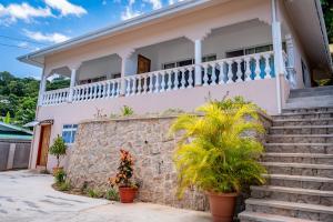 a house with a stone wall and stairs at Athara's Apartment in Anse Possession