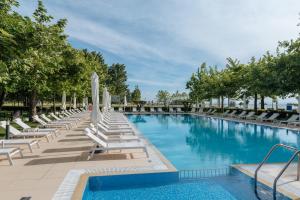 a large swimming pool with lounge chairs and umbrellas at Hotel Giannoulis in Paralia Katerinis