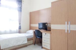 a bedroom with a bed and a desk with a television at Griya De Riz Syariah Mitra RedDoorz in Jambi
