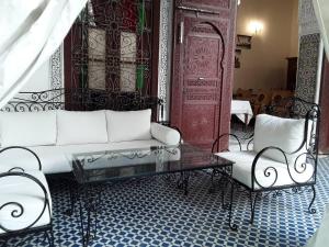 a living room with a white couch and two chairs at Riad Vega in Fès