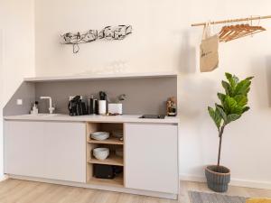 a kitchen with white cabinets and a potted plant at limehome Bamberg Maximiliansplatz in Bamberg