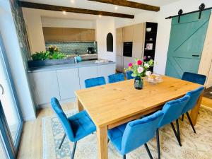 a dining room with a wooden table and blue chairs at Cottage Wilkenburg - das luxuriöse und idyllische Ferienhaus in Hemmingen