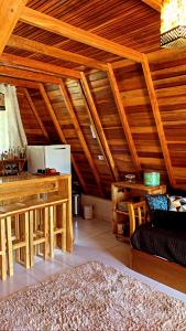 een woonkamer met houten plafonds en een keuken bij Chalé do Portal in Monte Verde