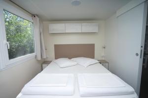 Cama blanca en habitación con ventana en Mobile Homes Camping Kovačine, en Cres