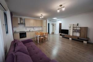 a living room with a purple couch and a kitchen at Tonitza Apartments in Cluj-Napoca