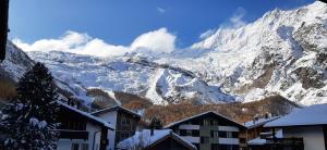 a snow covered mountain with houses in front of it at Amor Lodge in Saas-Fee