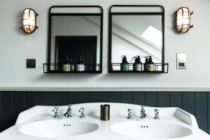 a bathroom with two sinks and two mirrors at Gara Rock in Salcombe