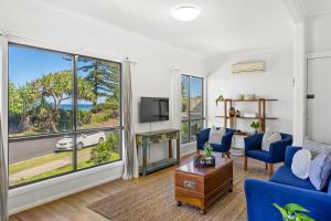 a living room with a blue couch and a large window at Surfside - Lennox Head in Lennox Head
