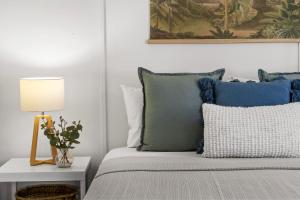 a bed with blue pillows and a table with a lamp at Surfside - Lennox Head in Lennox Head