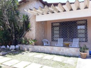 un patio con 2 sedie su un muro di mattoni di Ótima casa de praia com piscina a Rio das Ostras