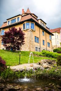 un bâtiment avec une fontaine en face d'un étang dans l'établissement Luxury Spa & Wellness Vila Valaška, à Luhačovice