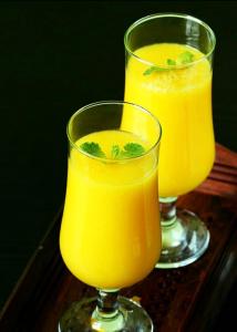 dos vasos de zumo de naranja en una mesa de madera en River Side Holiday Inn, en Weligama