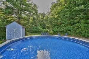 a large blue swimming pool next to a shed at Le Chalet Blue near Camelback Poconos, 6 Beds, Sleeps 10, Pool in Stroudsburg