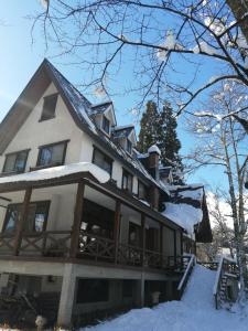 a large white house with snow on it at Pilot Lodge in Hakuba