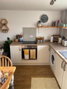 a kitchen with a stove and a washing machine at Cosy Cotswolds Self-Contained One Bedroom Cottage in Chipping Norton