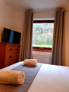 a bedroom with a bed with a television and a window at Letterfinlay Lodge House in Letterfinlay