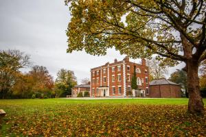 a large brick building with a tree in the foreground at YHA Chester Trafford Hall in Dunham on the Hill