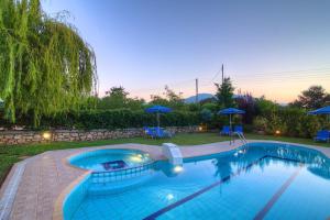 ein großer Pool im Hof mit Sonnenschirmen in der Unterkunft Villa Lambros in Roústika