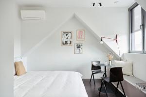 a white bedroom with a bed and a table at Edgar Guesthouse in Ghent