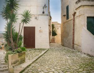 馬泰拉的住宿－SaxAurea，一条小巷,有一座有门和棕榈树的建筑
