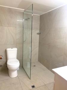 a bathroom with a toilet and a glass shower at Golden Beach Motor Inn in Caloundra