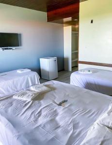 a room with two beds and a tv on the wall at Sistcep Praia Hotel in Luis Correia