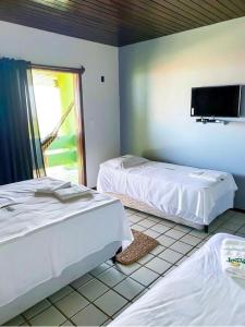 a bedroom with two beds and a tv on the wall at Sistcep Praia Hotel in Luis Correia
