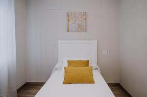 a white bed with a yellow pillow on it at San Rafael 4- Parking gratuito in Córdoba