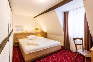 een kleine slaapkamer met een bed en een stoel bij Jäger's Landhaus Rössle in Niedernhall
