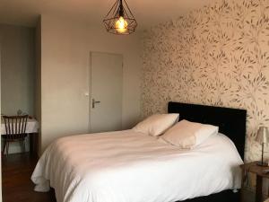 una camera da letto con un letto con lenzuola bianche e una lampada di Logis Le Cheval Blanc a Saint-Just