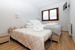 2 camas en una habitación con paredes blancas y ventana en Apartamento Besiberri Vielha, en Vielha