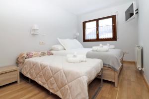 ビエラにあるApartamento Besiberri Vielhaの白い壁の客室で、ベッド2台、窓が備わります。