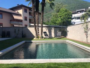 a swimming pool in a yard next to a building at Miranda, Modern Duplex, Garden, Swimming Pool, Parking in Losone