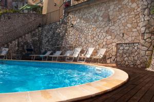 a swimming pool with chairs and a stone wall at Residence Zelzar in Vietri sul Mare