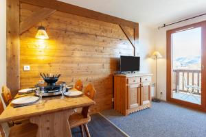 Habitación con pared de madera, mesa y TV. en Les Alpages du Corbier A003 en Le Corbier