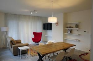 ein Wohnzimmer mit einem Holztisch und einem roten Stuhl in der Unterkunft ABC Boutique Apartments in Brügge