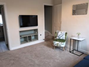 uma sala de estar com uma televisão e uma cadeira em Douglas House, near Hospital, attractive and comfy 2 bedroom House with enclosed yard to rear em Carlisle