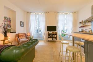 ein Wohnzimmer mit einem grünen Ledersofa und einer Küche in der Unterkunft le Tillot in Dijon