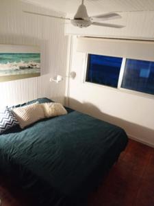 1 dormitorio con 1 cama con ventilador y ventana en Encantador departamento frente al mar 4 Amb en Villa Gesell