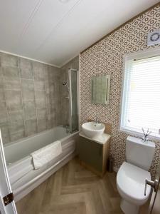 a bathroom with a toilet and a sink and a tub at Willow Lodge with Hot Tub in Barmby on the Moor