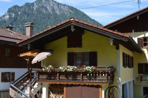 ein gelbes Haus mit einem Balkon mit Blumen darauf in der Unterkunft Ferienwohnung Haus Florence in Schönau am Königssee