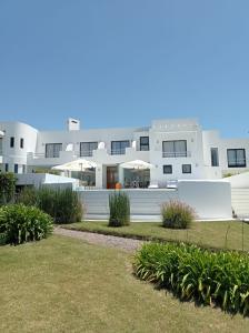 a white building with a lawn in front of it at Posada de los Pajaros in Punta del Este
