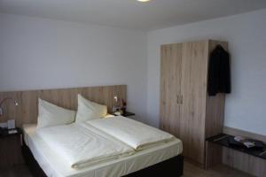 Schlafzimmer mit einem weißen Bett mit einem Kopfteil aus Holz in der Unterkunft Eichenhof Hotel GbR in Eislingen