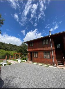 um edifício de madeira com um banco à frente em Cabañas-apartamentos Borde Río em Neltume