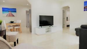 uma sala de estar com uma televisão de ecrã plano numa parede branca em Miami-Airport Oasis VIP House em Miami