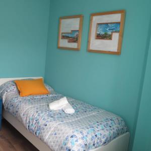 1 dormitorio azul con 1 cama con 2 cuadros en la pared en Las 3 Golondrinas, en Peñafiel