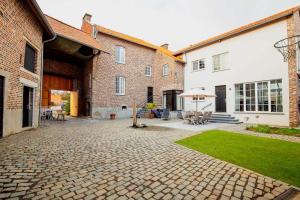 een binnenplaats met een bakstenen gebouw en een patio met een parasol bij Villa de Daelhoeve luxurious with big garden in Heers