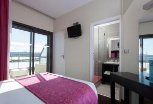 a bedroom with a pink bed and a bathroom at Hôtel Baptistin in Le Lavandou