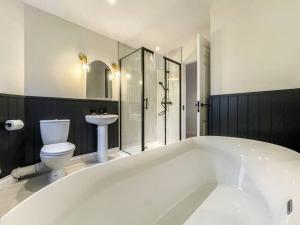 a large white bath tub in a bathroom with a toilet at Hareshaw House in Bellingham